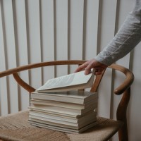 stack of books sitting on a chair with a hand grabbing the top book